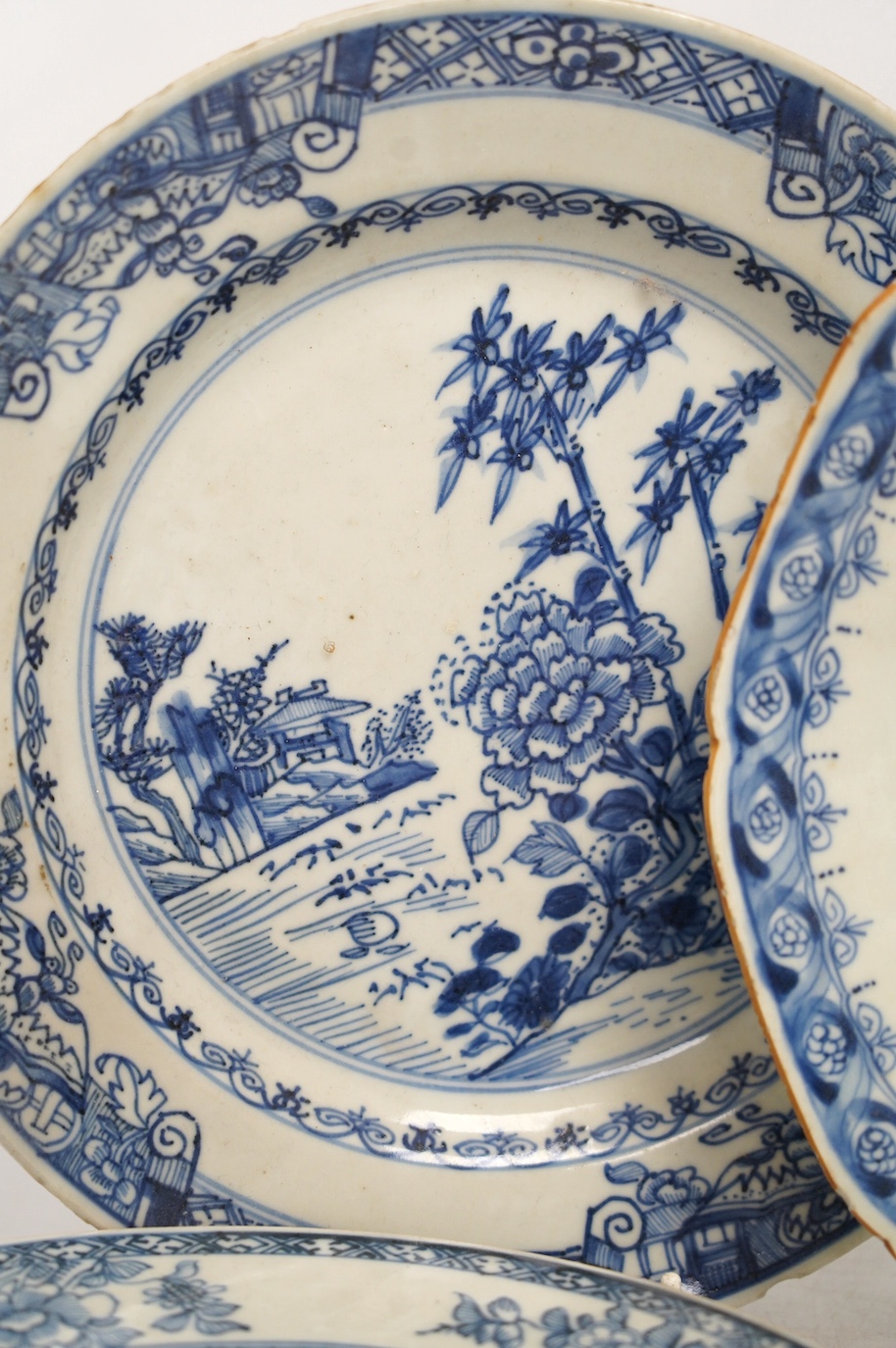 Four Chinese blue and white export plates and a rice bowl, bowl 24.5cm diameter. Condition - poor to fair, some damage to the edges